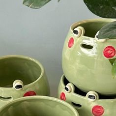 three green ceramic pots with red and black polka dots, one has eyes on it