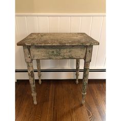 an old wooden table sitting on top of a hard wood floor next to a wall