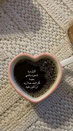 a heart shaped coffee mug sitting on top of a table next to a spoon and bowl