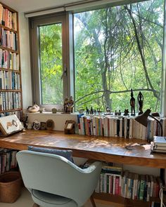 a chair sitting in front of a window next to a book shelf filled with books