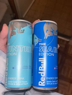 two cans of energy drink being held by someone