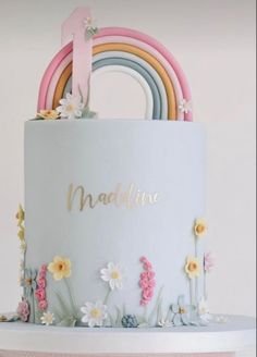 there is a cake with flowers and a rainbow on the top that says naddivine