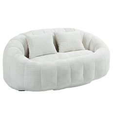 a white round couch with four pillows on it's back and one pillow in the middle