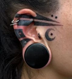 a woman with ear piercings has an artistic design on her face and behind her ear