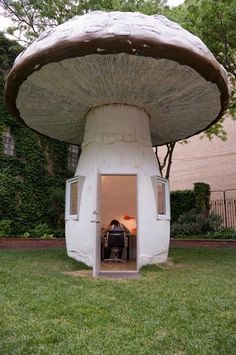 a large mushroom like structure sitting in the middle of a lawn with a person inside