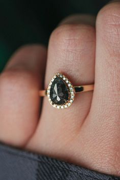 a woman's hand holding a ring with a black and white diamond on it