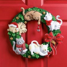 a christmas wreath with cats and kittens hanging from it's side on a red door