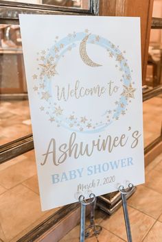 a welcome sign for a baby shower is displayed in front of a window with the words, welcome to ashwine's baby shower written on it