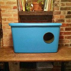 a blue plastic box sitting on top of a wooden shelf next to a brick wall