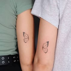 two people with matching tattoos on their arms, one is holding the other's arm