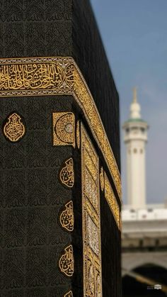 an intricately decorated black and gold building with a white mina tower in the background