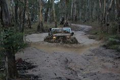 an off - road vehicle driving through mud in the woods