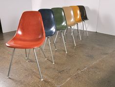 five chairs lined up in a row on the floor, all different colors and sizes