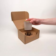 a hand holding a cup in a cardboard box