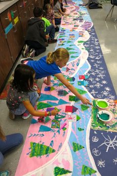 children are sitting on the floor and playing with their paper crafts at an art class