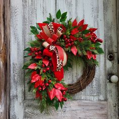 a wreath with poinsettis and greenery is hanging on a wooden door