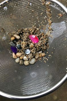 a metal strainer filled with rocks and gravel