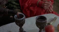 two silver candles are sitting on a table with apples and other items around it,