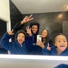 a group of people taking a selfie in front of a mirror with their hands up