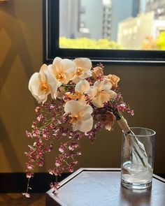 a vase filled with flowers sitting on top of a wooden table next to a window