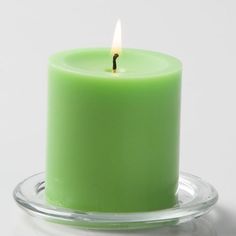 a green candle sitting on top of a glass plate