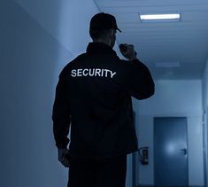 a security man standing in a hallway with his back to the camera and looking at something