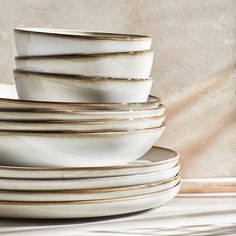 a stack of white plates stacked on top of each other in front of a beige wall