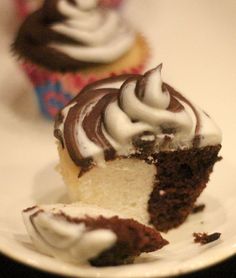 two cupcakes with white frosting and chocolate icing are on a plate