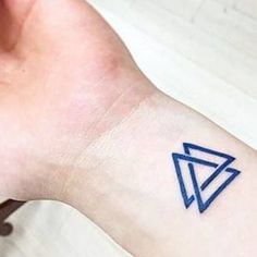 a small blue triangle tattoo on the left inner arm and wrist, with an arrow in the middle