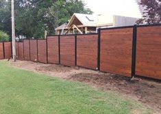 a wooden fence in the middle of a yard with grass and dirt on the ground