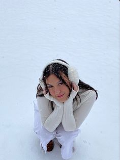 a woman kneeling in the snow with her hands on her head