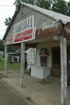 an old building with signs on the front and side of it that says budweiser bar - bq