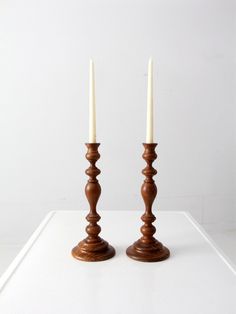 two wooden candlesticks sitting on top of a white table