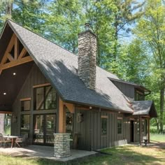 a small cabin in the woods with a stone chimney and wood trimmings on the roof