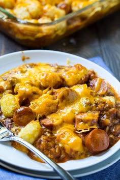 a white plate topped with sausage and tater tot casserole next to a fork