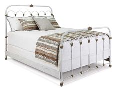 a white bed with metal frame and pillows