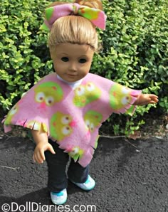 a doll with blonde hair wearing a pink and green ponchy top, black pants and blue shoes