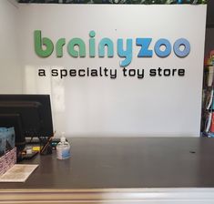 a desk with a computer on it in front of a sign that says brainyzoo