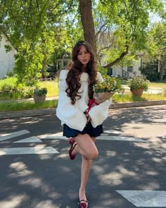 a woman is walking down the street with flowers in her hand and she has long brown hair