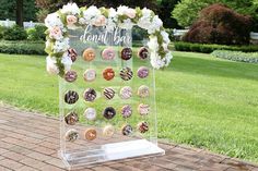 a clear acrylic sign with doughnuts on it and flowers in the background