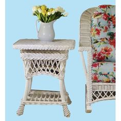 a white wicker table and chair with flowers in a vase next to it on a blue background