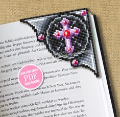 an open book with a cross on the front and back cover in pink, black and white