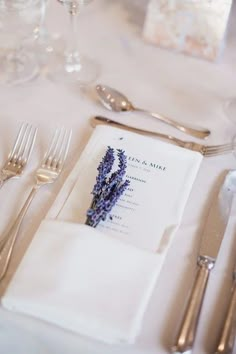 the place setting is set with silverware and napkins, along with lavender flowers