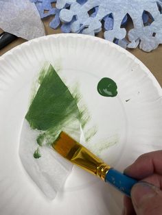 a paper plate with a green tree on it and a paintbrush in the middle