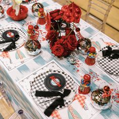 the table is set up with red roses and black vinyl record records on it, along with other decorations