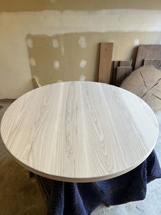 a wooden table sitting on top of a floor next to a pile of wood planks