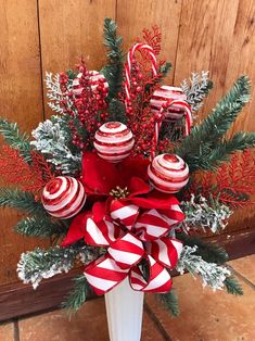 a white vase filled with candy canes and christmas decorations