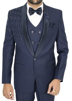 Elegance personified, this navy blue wedding tuxedo suit redefines formal attire. Its exquisite hand-embroidery, brimming with intricate details, transforms it into a masterpiece fit for any grand occasion. The shawl lapel, a hallmark of sophistication, elevates this suit to a league of its own. Every stitch, every thread, bears witness to the meticulous craftsmanship that went into creating this remarkable ensemble. From the precise tailoring to the hand-embroidered embellishments, it's a testament to timeless artistry. Whether you're stepping into the role of the groom, an honored guest, or simply a style connoisseur, this tuxedo suit is your ticket to leaving an indelible mark. It embodies a timeless quality that not only impresses but lingers in memory, ensuring it holds a treasured pl Tailored Suits For Wedding And Gala, Blue Tuxedo Three-piece Suit For Party, Fitted Blue Sherwani For Groom, Blue Fitted Sherwani For Groom, Formal Blue Embellished Sets, Blue Embellished Formal Sets, Blue Tuxedo Blazer For Wedding, Royal Blue Notch Lapel Suit For Wedding, Blue Tuxedo Style Three-piece Suit For Wedding