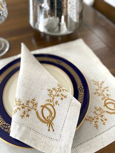 a place setting with two napkins on top of each other and a glass vase in the background