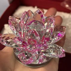 a hand holding a pink crystal flower in a box